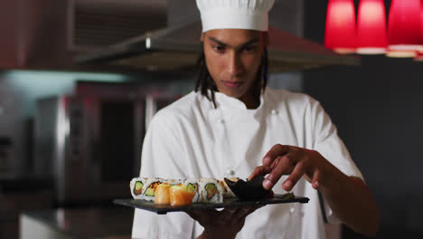cocinero de raza mixta de pie en la cocina haciendo un buen plato de sushi