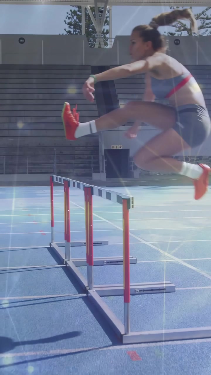 Video verticale: Ostacolista di atletica leggera che scatta su pista blu, si avvicina e supera un ostacolo con scintille