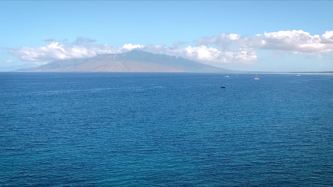 Aerial view of a blue sea open water with white clouds and island. Aerial.