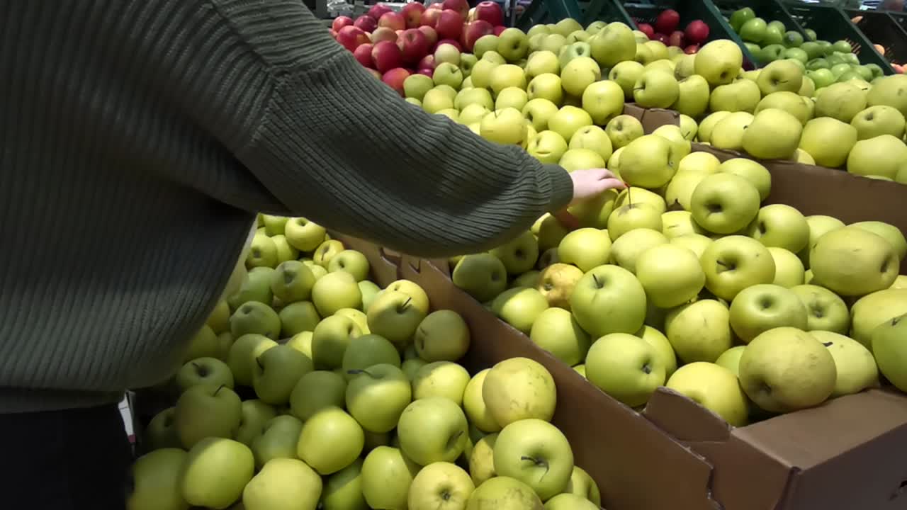 niña comprando manzanas doradas en el hipermercado