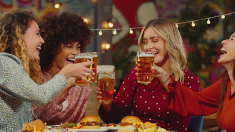 multi-cultural female friends sitting at table eating meal in restaurant enjoying girls night out