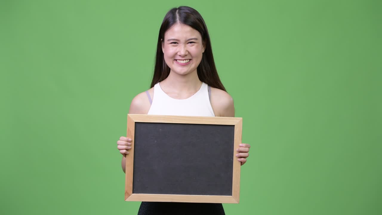 Young beautiful Asian businesswoman holding blackboard