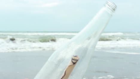 young man opening message in a bottle on sand beach