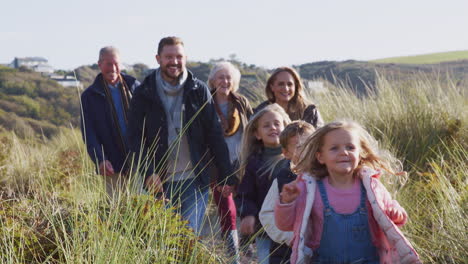 multi-generation family walking along path through hills in countryside together