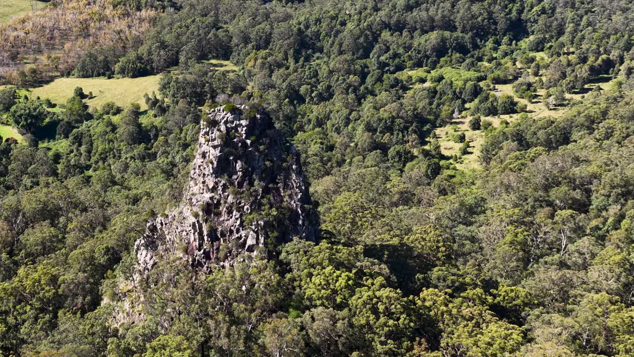 Aerial footage showcasing Nimbin Rocks surrounded by dense forest and greenery in bright daylight
