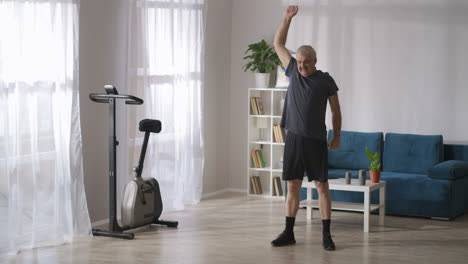 Un-Anciano-Está-Haciendo-Gimnasia-En-Su-Apartamento-El-Domingo-Por-La-Mañana-Preocupándose-Por-La-Salud-De-Las-Articulaciones,-Ejercicios-De-Respiración.