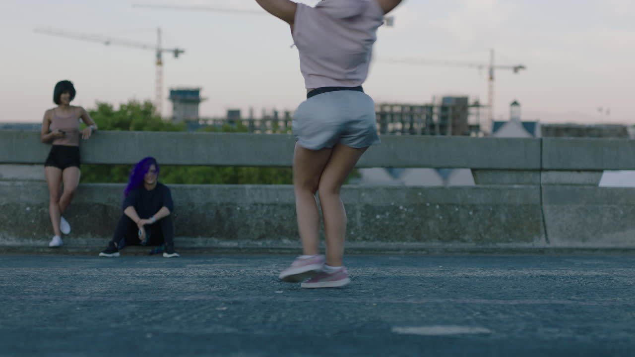 mujer bailarina atractiva joven bailarina de raza mixta realizando baile callejero de estilo urbano en la ciudad practicando movimientos de estilo libre amigos viendo disfrutando pasar el rato al atardecer