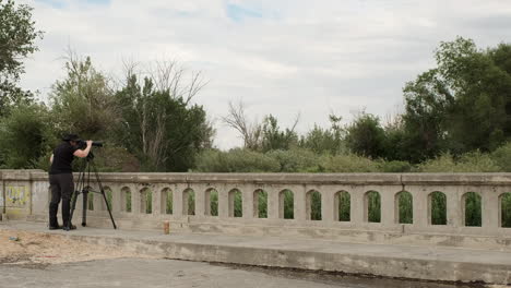 nature photographer woman in black uses large camera on sturdy tripod