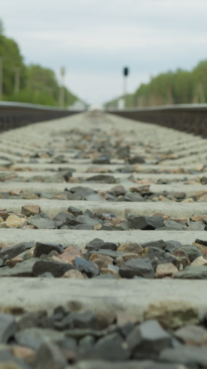 철도 트랙의 클로즈업 빠른 시각은 콘크리트 스프레이어와 자갈 발라스트에 초점을 맞추고, 지평선으로 향하는 관점입니다.