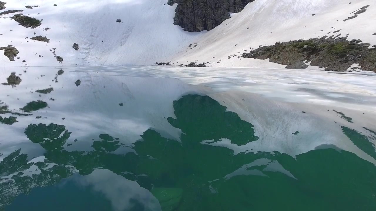 Flyfoto av delvis frossen fjellsjø i fjellene