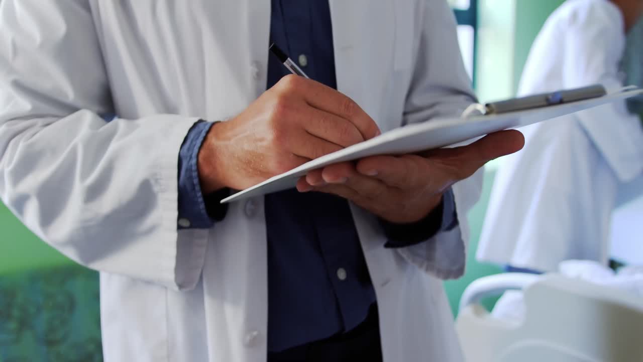 Médico escribiendo en un portapapeles en la sala 4k