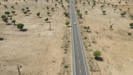 aerial drone shot of a vehicle silhouetted against the golden desert horizon of rajasthan.