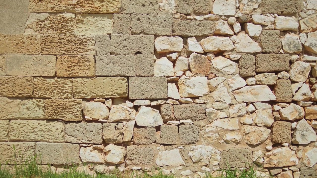 Antico muro in pietra calcarea e muratura mista rivela secoli di tecniche di restauro presso il Castello Svevo a Brindisi, Puglia, Italia, ripresa statica di dettaglio architettonico.
