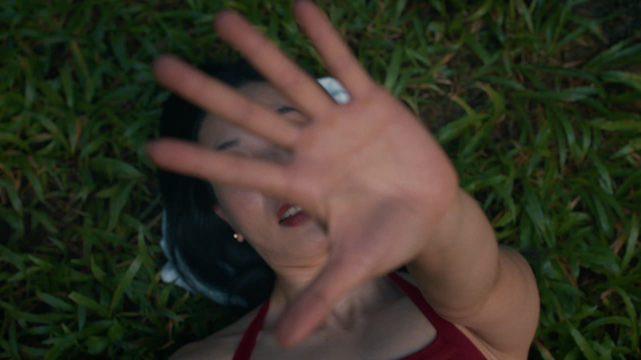 Woman lying on grass with hand in front of face