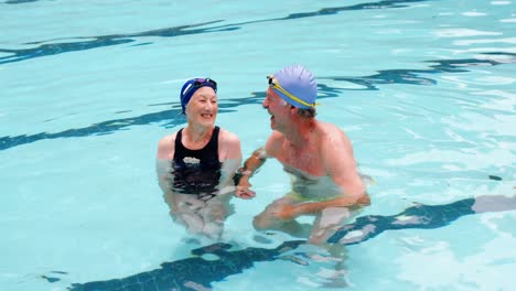 senior couple swimming in the pool with inflatable tubes