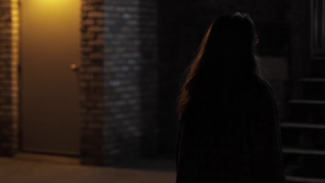 Tracking-Shot-Of-A-Young-Woman-Walking-Up-Stairs-In-Complete-Darkness