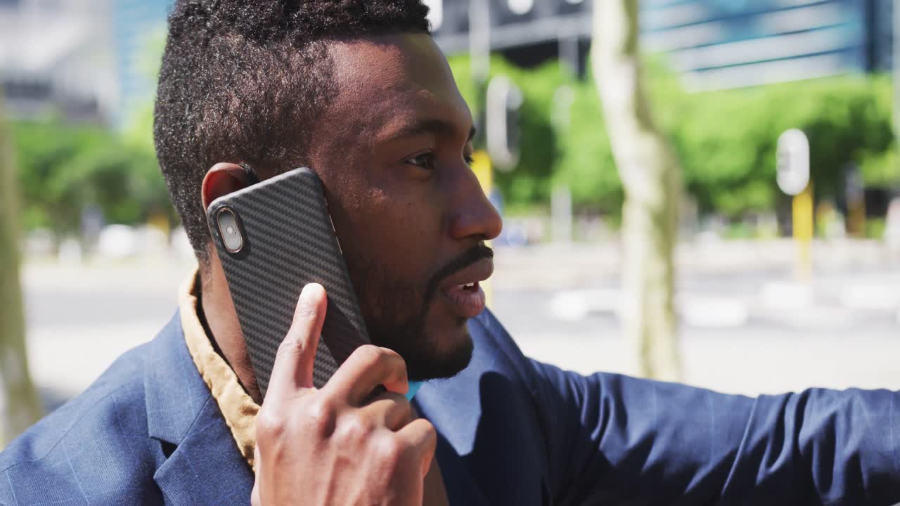 hombre de negocios afroamericano hablando por teléfono inteligente en la calle de la ciudad