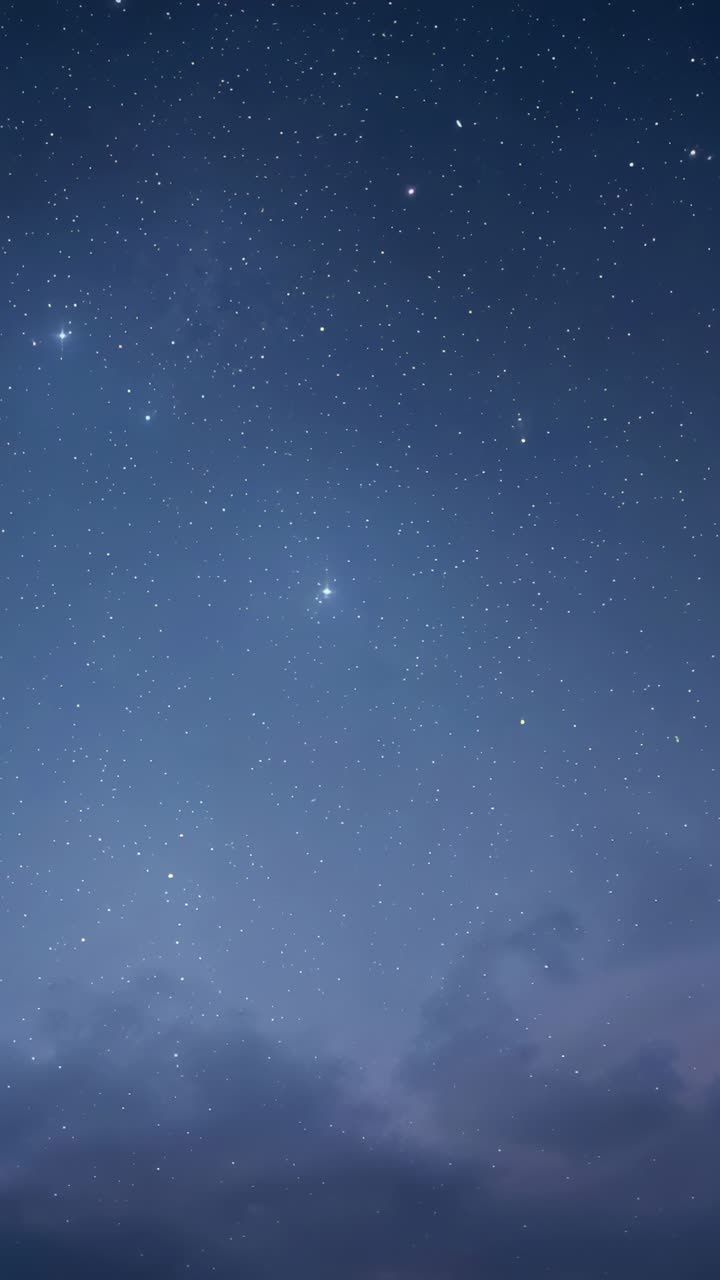 Vertical video: Shining sky with bright stars twinkling from haze at dark horizon, clouds drifting