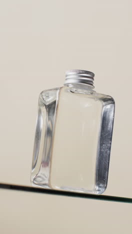video vertical de una botella de producto de belleza en un estante de vidrio con espacio de copia en un fondo blanco