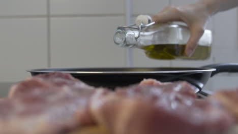 disparo de enfoque selectivo, como verter aceite en una sartén, carne deliciosa en el primer plano borroso