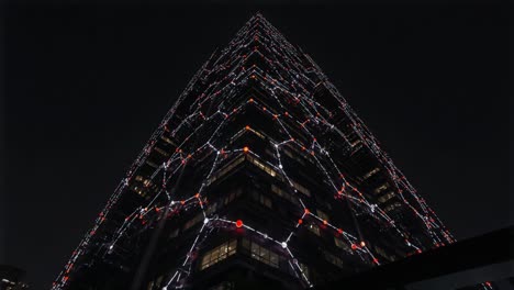 a mesmerizing transformation: the nighttime illumination of a modern skyscraper, showcasing dynamic light patterns and architectural elegance