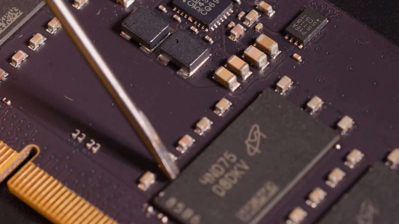 Macro view of a metal probe inspecting electronic components on a purple computer circuit board