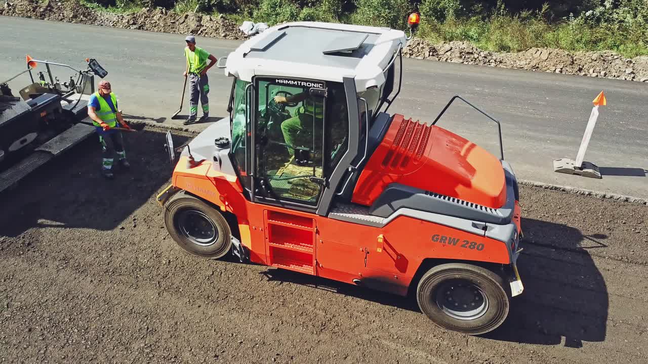 Large road-roller paving a road. Road construction. Aerial view.