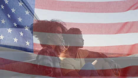 Animation-of-American-flag-waving-over-mixed-race-couple-on-beach-by-seaside