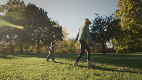 A-woman-has-fun-with-her-baby,-running-together-on-the-grass-in-the-rays-of-the-sun