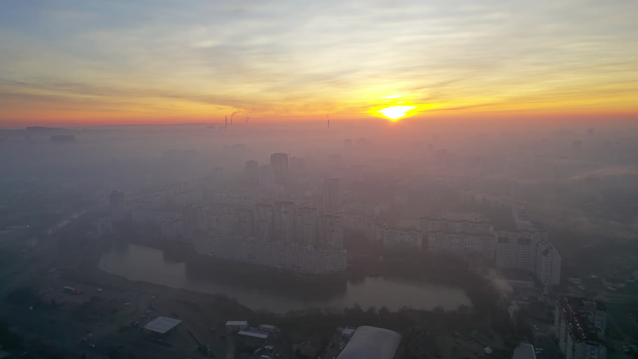 Aerial drone view of Chisinau at sunrise, Moldova. View of the city with fog in the air, multiple buildings, roads, lake, bare trees
