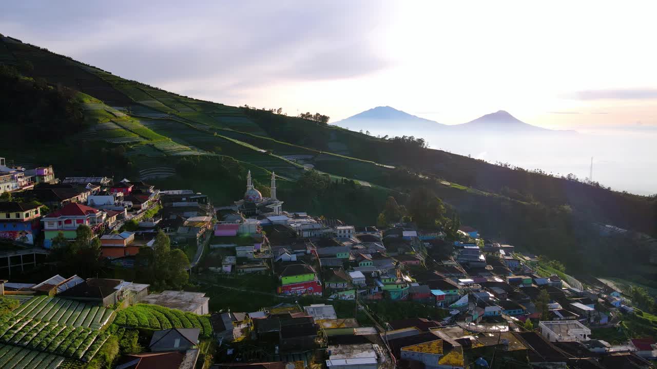 Aerial panning view revealing the picturesque village of Nepal Van Java in the slope of a volcano at sunset