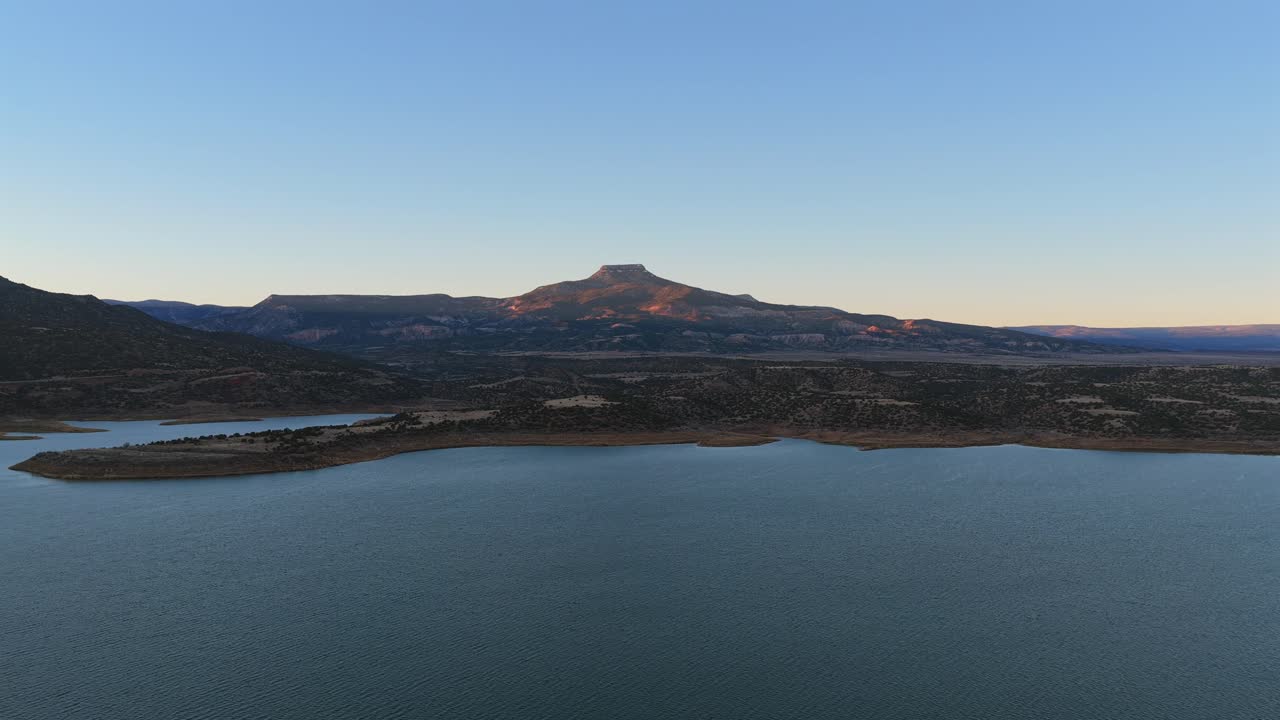 Wide aerial shot revealing the famous Cerro Pedernal mesa and the water of Abiquiu Lake. This classic New Mexico landscape was a primary subject for the iconic artist Georgia Okeeffe