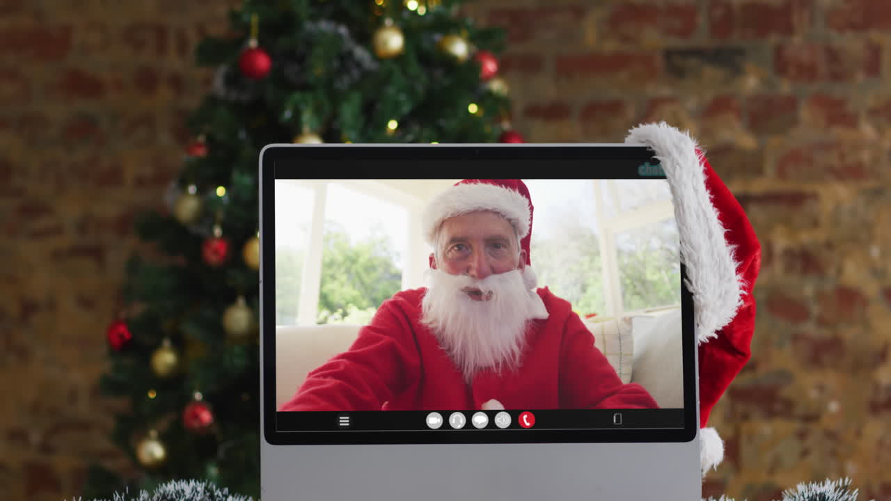 hombre caucásico senior en disfraz de santa en llamada de video en la computadora, con decoraciones de navidad y árbol