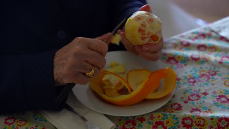 precise elderly hands peel tangerine with knife meticulously