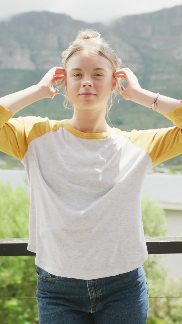 Vertical video of happy caucasian teenage girl in yellow and white long sleeved t shirt, copy space