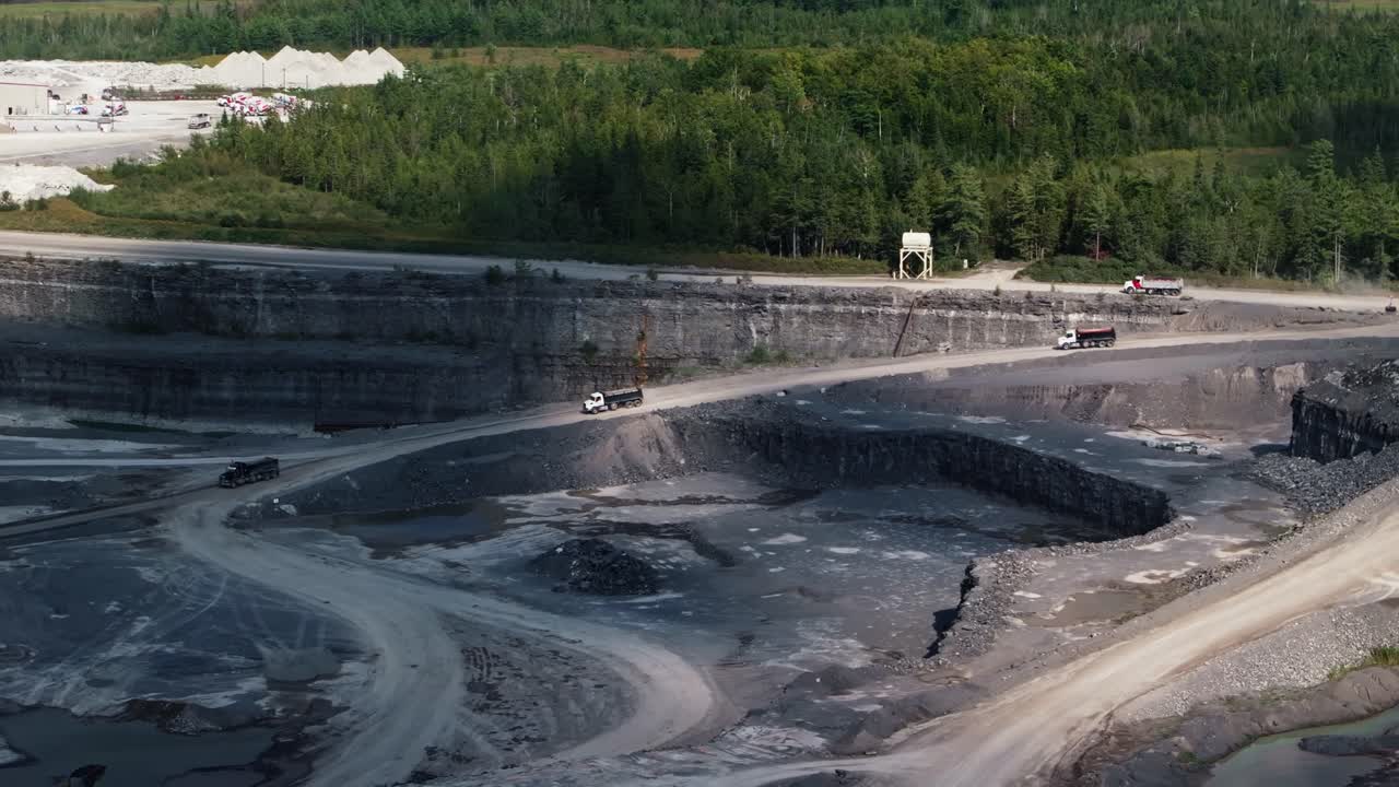Wide angle establishing shot trucks and lorries driving in quarry mine
