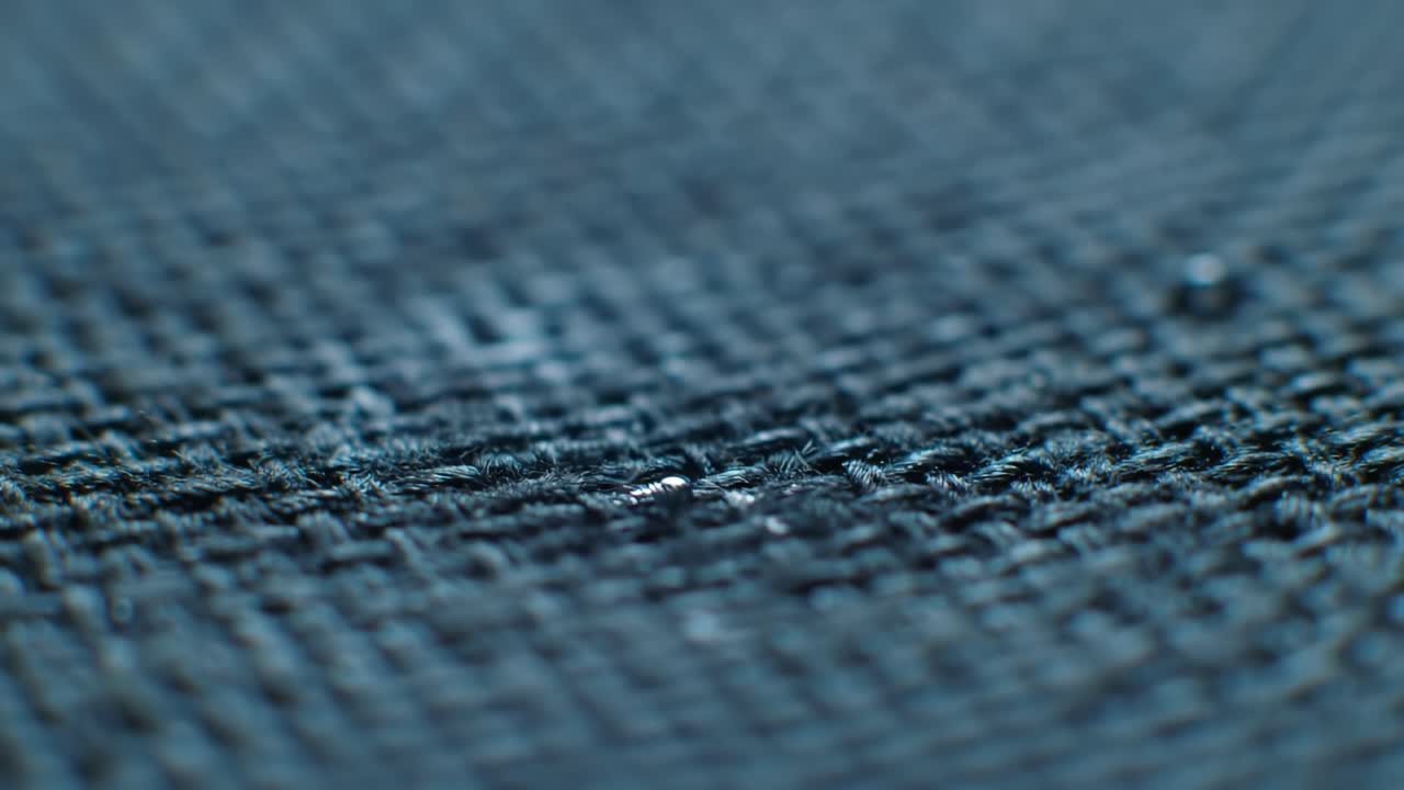 View a close-up of water droplets forming on a fabric surface. This demonstration highlights the effectiveness of waterproof technology and showcases material resistance to liquid penetration.