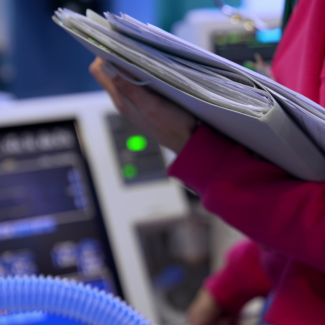 Unrecognized doctor holding medical paper documents. Medic comes up to the medical equipment in surgery room