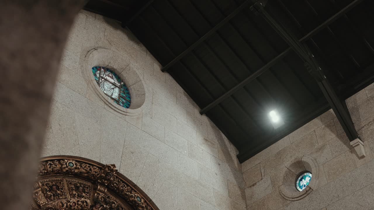 Vista verso l'alto del soffitto di una chiesa in pietra con vetrate rotonde