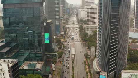 Aerial-pedestal-shot-ascending-between-two-skyscrapers-of-vehicles-on-a-busy-multi-lane-motorway-in-modern-city-center-of-Jakarta