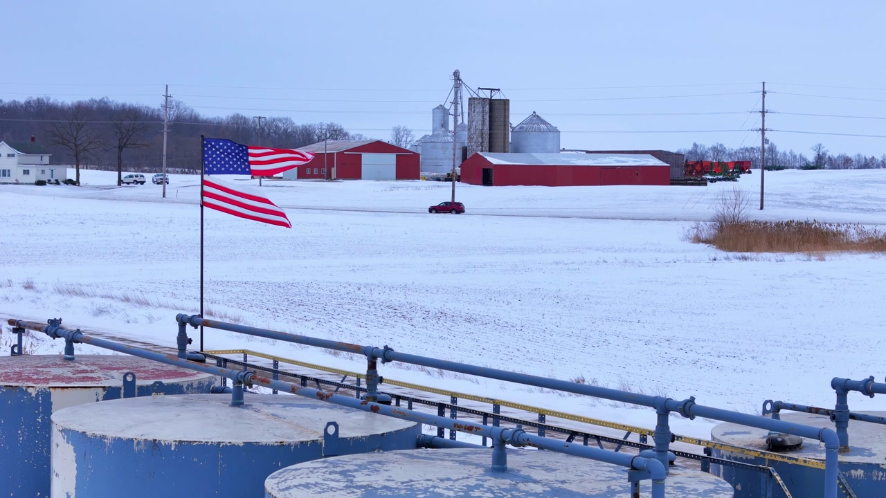 Torn American flag flying on a winter farm in Saline, Michigan, USA