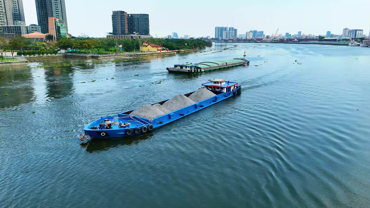 Aerial: freighter sand on the Saigon River during the day in Ho Chi Minh City, Vietnam, establishing drone shot