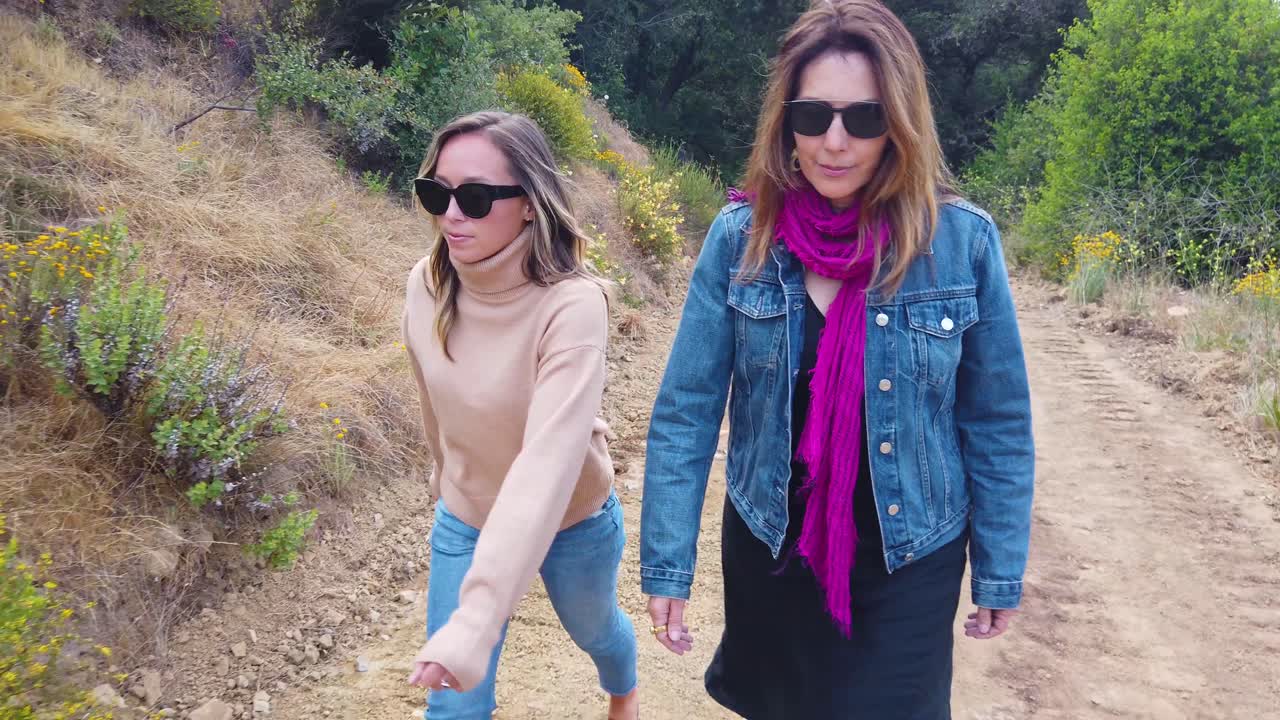 Una madre y su hija caminan a cámara lenta por un sendero en las montañas de Santa Bárbara, California