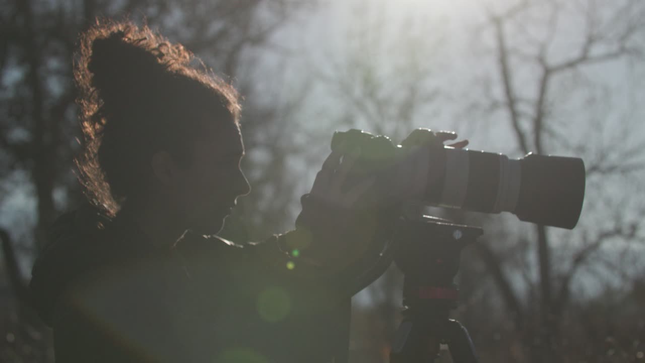 Beautiful female wildlife photographer with tripod in nature in Colorado