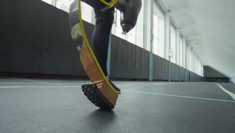 man with prosthetic running blade training in stadium