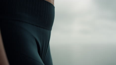 Fit-woman-body-wearing-jeggings-on-beach-close-up.-Sportswoman-standing-seacoast