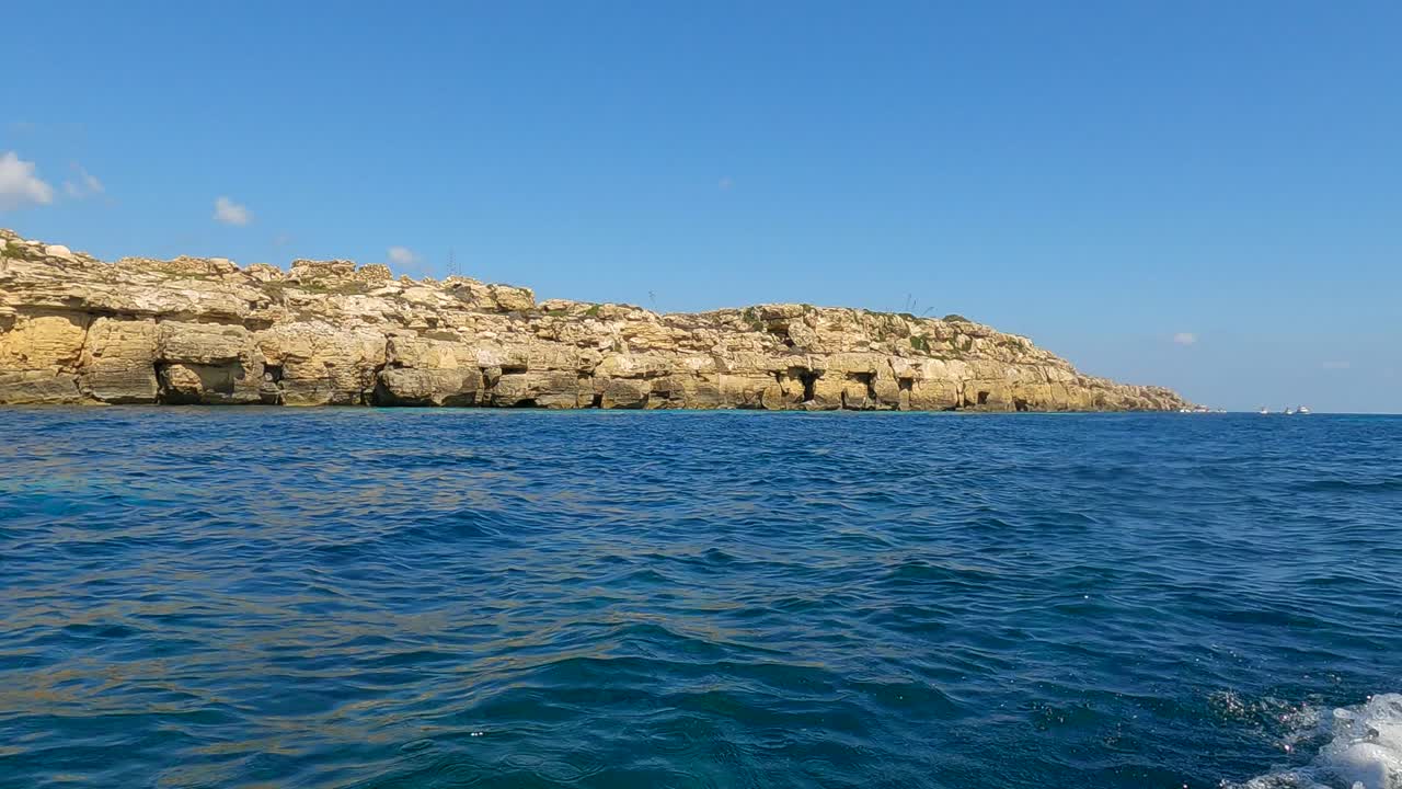 Low-angle sea-level view from cruising boat of Favignana island coastline and turquoise sea water in Sicily, Italy