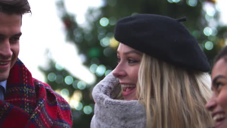 friends stand in front of christmas tree on south bank in london