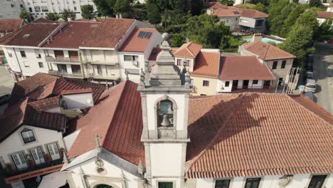 Belltower-and-majestic-colorful-rooftops-of-Arouca-town-in-Portugal,-aerial-orbit-view