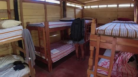 woman with heavy backpack walks to hostel bunkbeds in guatemala